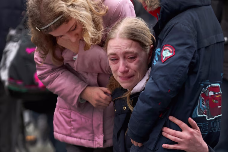 Image: A woman embraces her children at Place de la Bourse