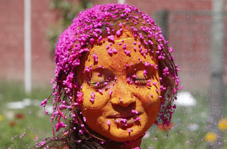 Image: A students with her face smeared in coloured powder, celebrates Holi at a university campus in Chandigarh