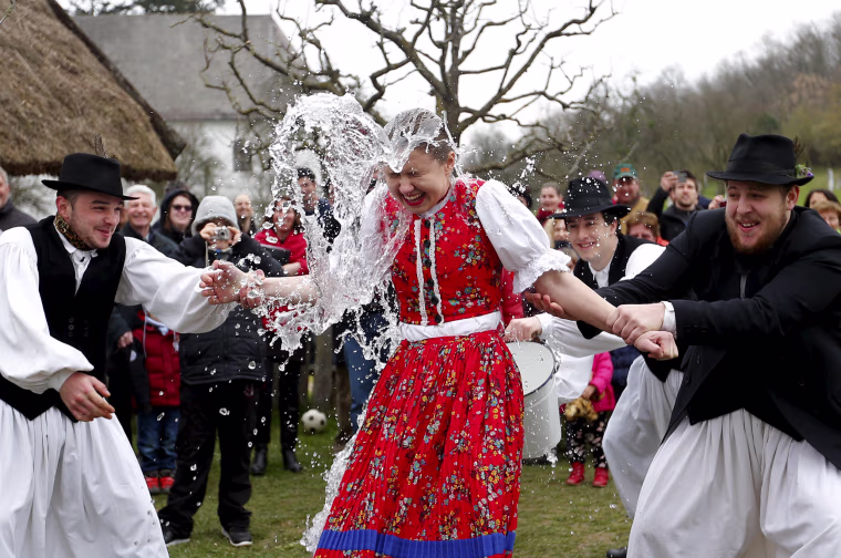 Image: Men throw water on a woman as part of traditional Easter celebrations in Szenna
