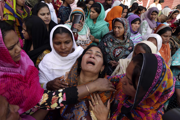 Image: People try to comfort a Pakistani Christian mother during the funeral of her two daughters