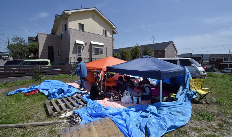 Image:A family sits in a tent after being evacuated from their home