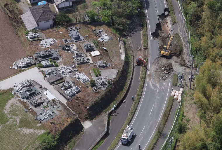 Image: An aerial view of construction workers restoring a damaged road located next to a grave yard
