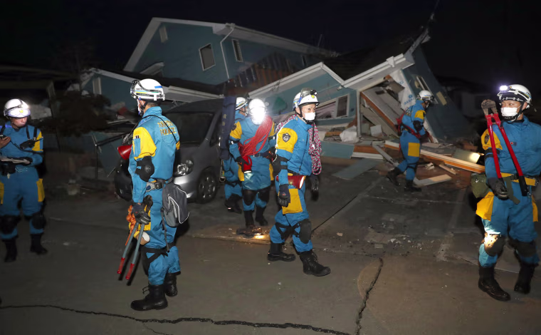 Image: Police officers investigate a house collapsed by an earthquake