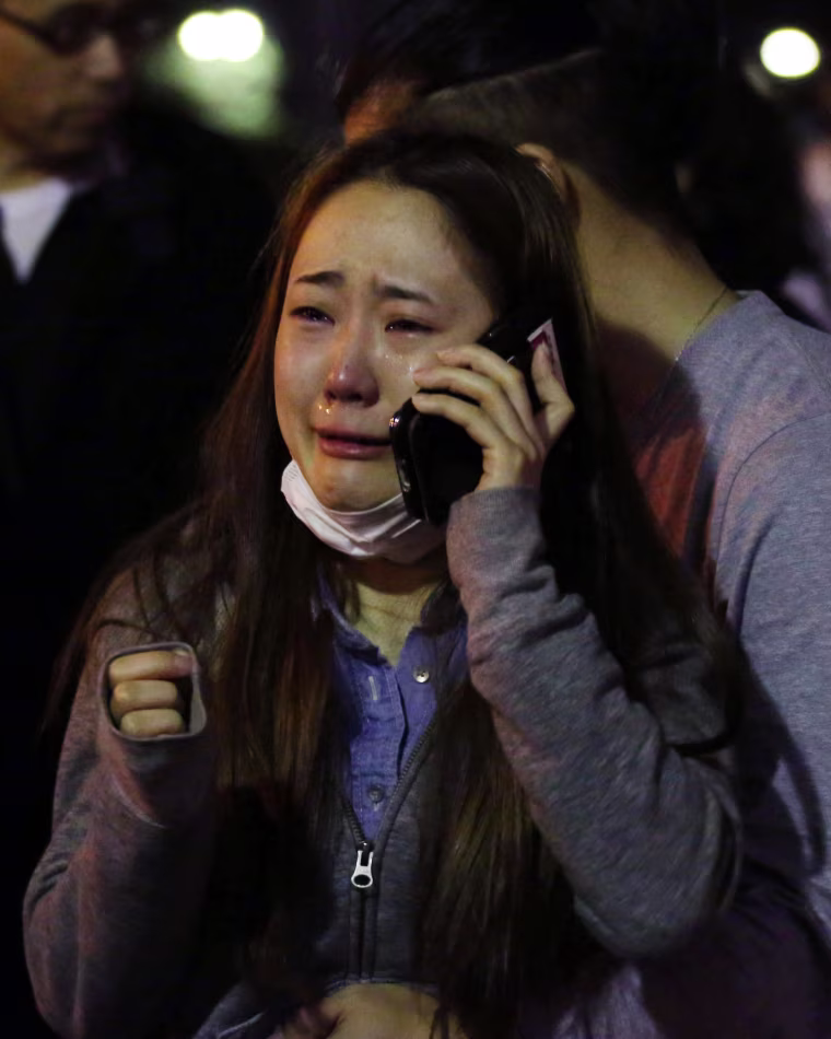 Image: An evacuee cries as she talks on a mobile phone at a park in Kumamoto