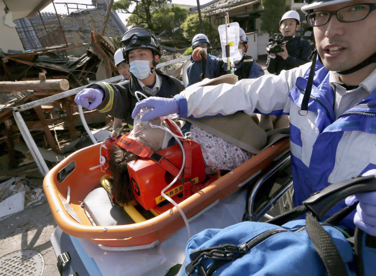 Image: A woman is carried out after being rescued from a house collapsed by an earthquake