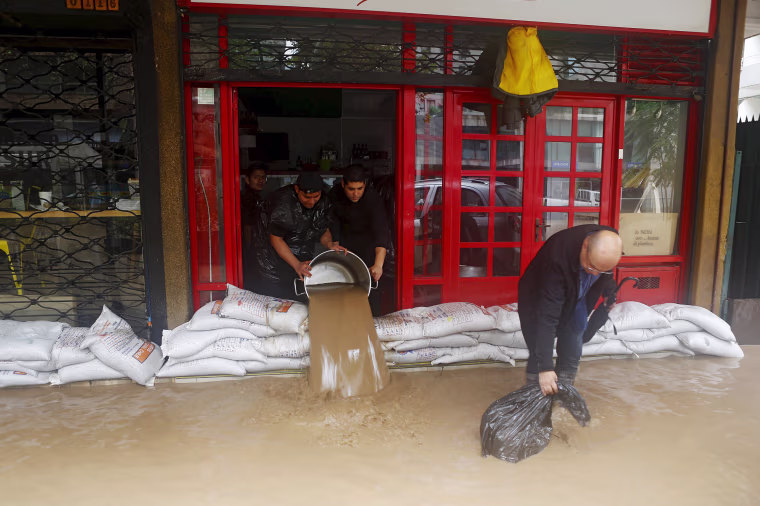 Image: Workers remove water from a store in a flooded street in Santiago