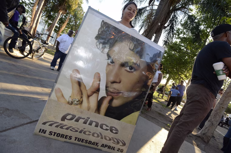 Image: A fan holds a poster of late musician during a gathering to pay tribute to his life and work in Los Angeles, California