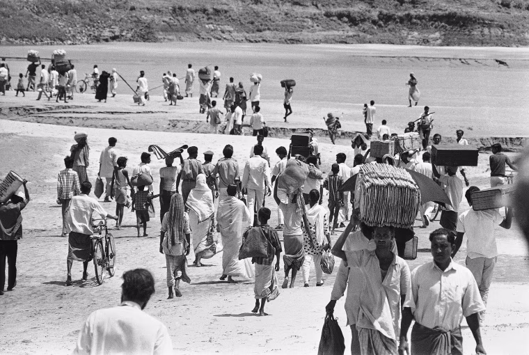 Carrying their few worldly possessions, Bengalis stream across the shallows of the River Ganges Delta at Kushtia, East Pakistan, to escape from the advancing troops of the West Pakistan army fighting near Goaiubogath on April 8, 1971.