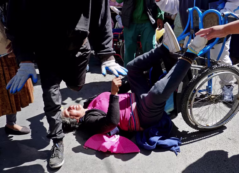 Image: A demonstrator with physical disability falls from a wheelchair during a protest to demand that the government increase the monthly disability subsidy in La Pazwith physical disabilities