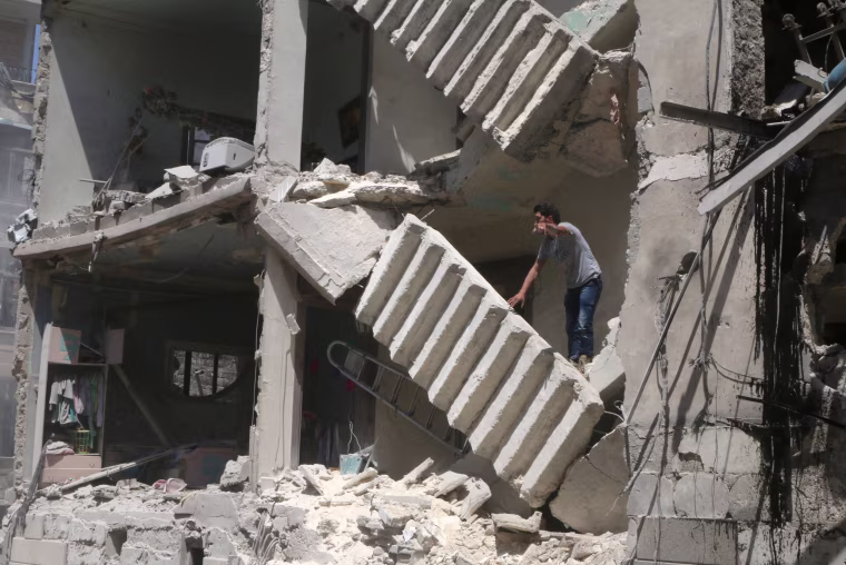 Image: A man gestures as he stands on a damaged building at a site hit by airstrikes in the rebel held area of al-Kalaseh neighbourhood of Aleppo