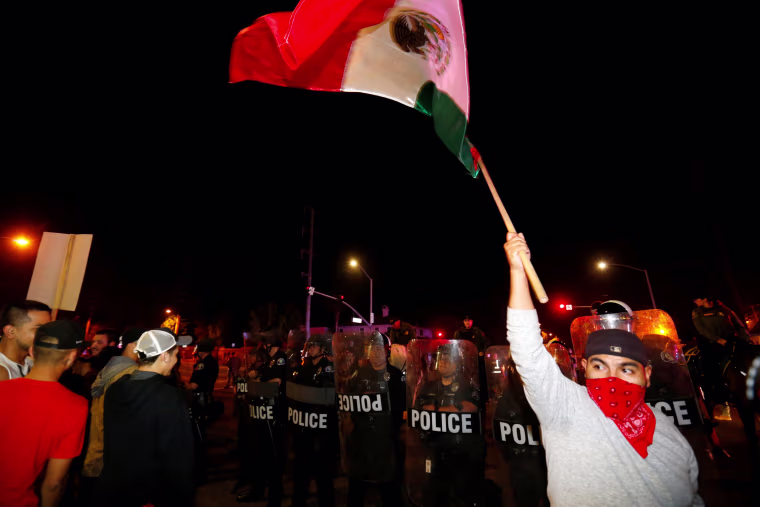 Image: Police in riot gear form a line to begin to break up a group of protesters outside Republican U.S. presidential candidate Donald Trump campaign rally in Costa Mesa