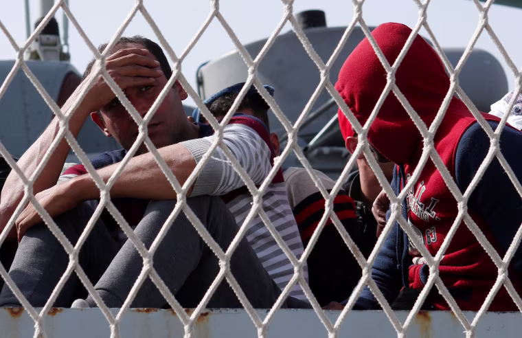 Image: Migrants are seen before to disembark from Italian navy ships \"Bettica\" in the Sicilian harbour of Porto Empedocle