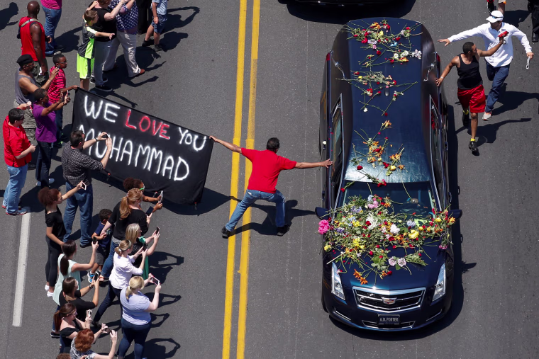 Image: Well wishers holding a banner touch the hearse carrying the body of Muhammad Ali in Louisville Kentucky