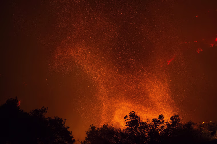 Image: A fire whirl, or fire tornado, rises from advancing flames in the early morning hours
