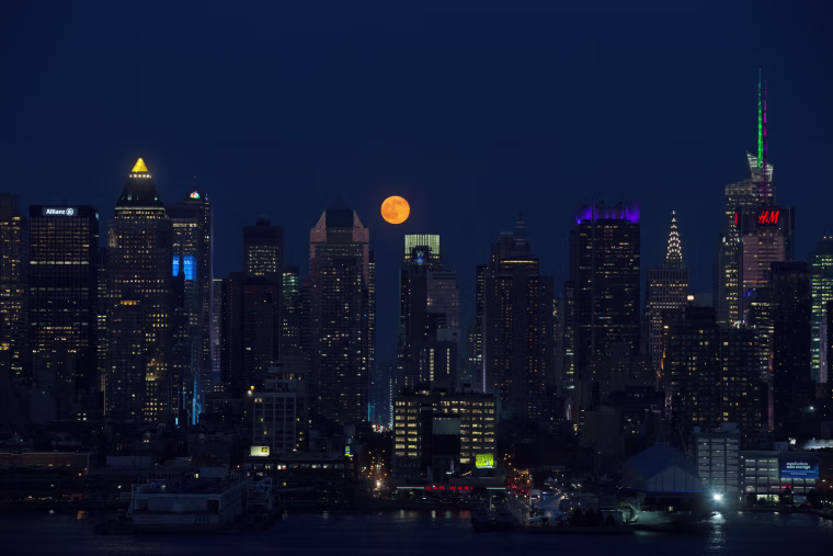 Image: The moon rises above skyscrapers in Manhattan, New York