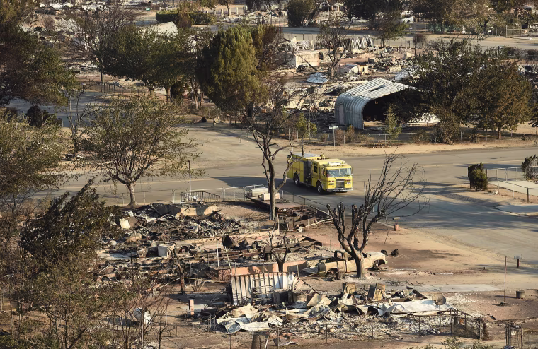 Image: A firetruck drives through a neighborhood decimated by the Erskine Fire in South Lake