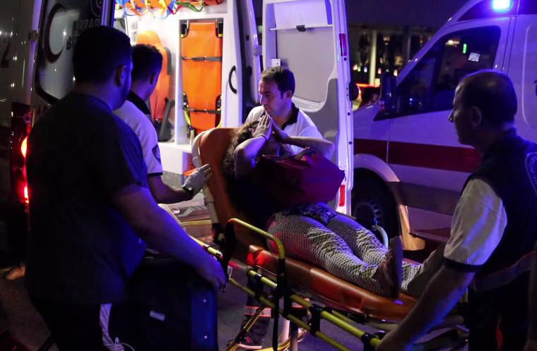 Image: An injured woman covers her face as she is carried by paramedics into ambulance at Istanbul Ataturk airport, Turkey, following a blast