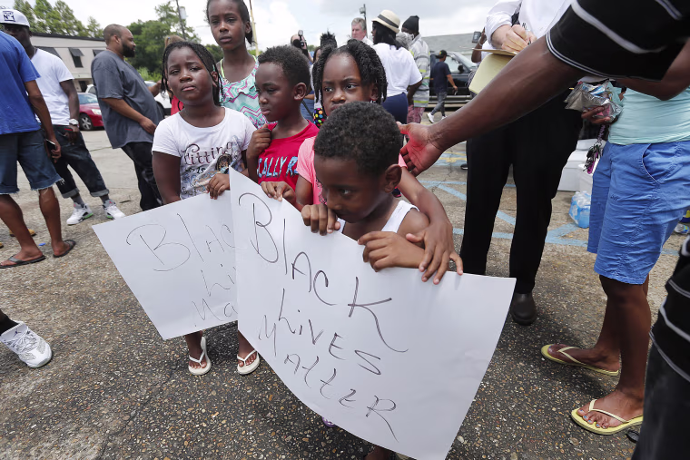 Image: Children hold signs reading \"Black Lives Matter\" outside the Triple S convenience store in Baton Rouge