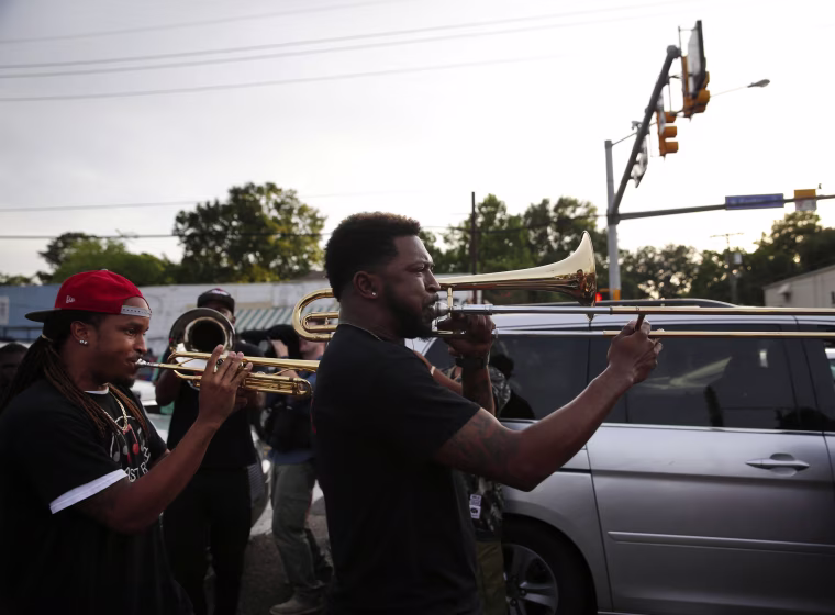 Image: A brass band marches through the street after a vigil for Alton Sterling