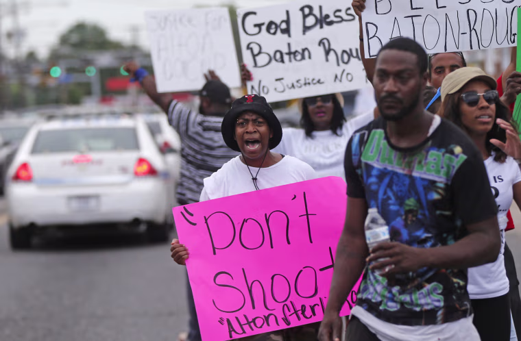 Image: People demonstrate in the street as police cars pass outside the Triple S convenience store in Baton Rouge