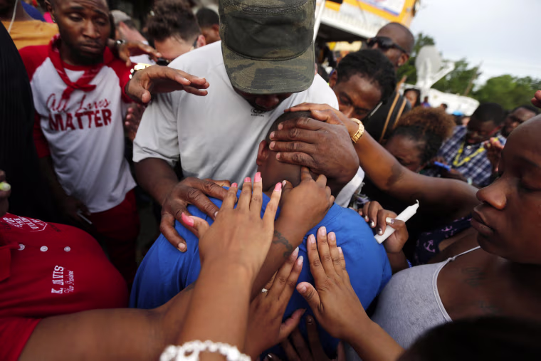 Image: Cameron Sterling, son of Alton Sterling, is comforted by hands from the crowd at a vigil