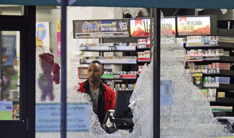 Image: A clerk looks at broke windows shot out at a store in downtown Dallas