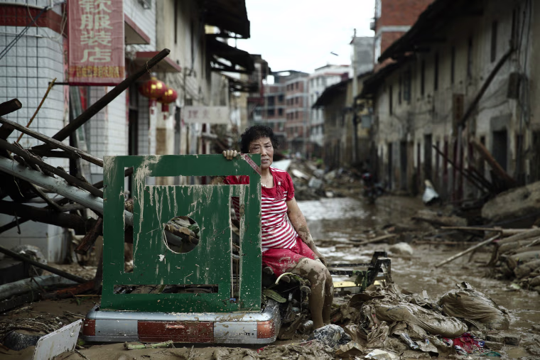 Image: A woman sits on ruins after typhoon Nepartak swept through Minqing county