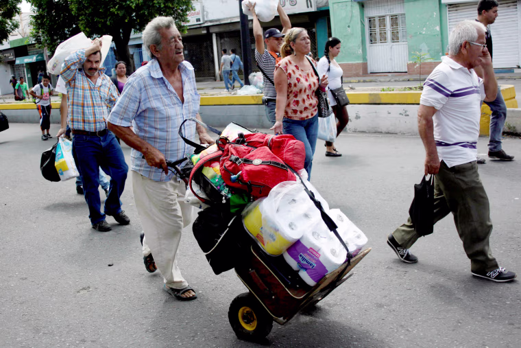 Image: A man push a trolley with toilet paper and other goods as he walks towards the Colombian-Venezuelan border after shopping in Cucuta, Colombia