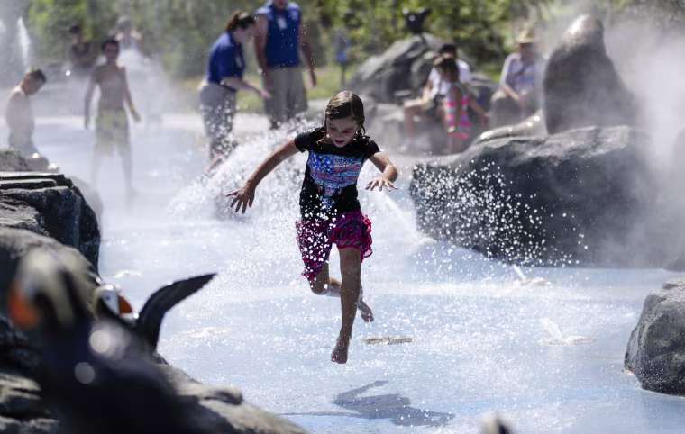 A child cools off at the Alaskan Adventure splash pad at the Henry Doorly Zoo in Omaha, Neb., on July 21, as high temperatures and humidity affect much of the central U.S., making it feel as hot as 115 degrees Fahrenheit in some places and leading some cities to open cooling stations and take other precautions.