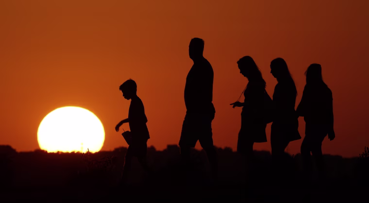 The sun sets beyond visitors to Liberty Memorial on Thursday, July 21, 2016, as the temperature hovers around 100 degrees in Kansas City, Mo. A high pressure system, sometimes called a \"heat dome,\" will push conditions to their hottest point so far this summer, though record hot temperatures are not expected, according to the National Weather Service. (AP Photo/Charlie Riedel)
