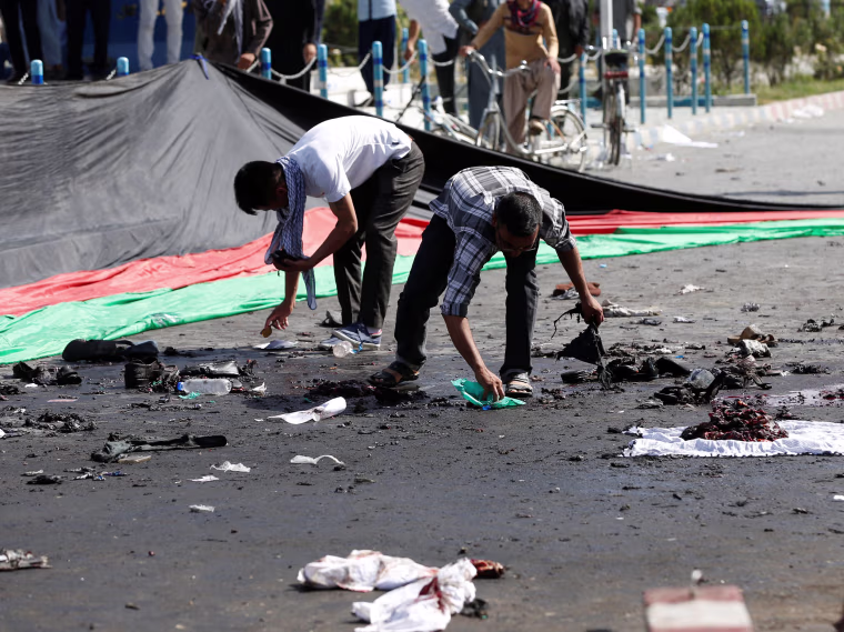 Image: Afghan men remove the remained clothes of victims from the ground after a suicide attack in Kabul