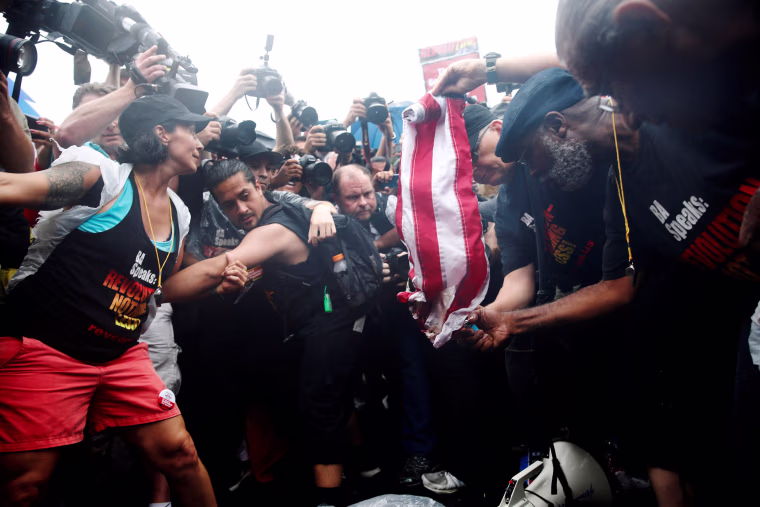 Image: A group of communists opposed to all the presidential candidates attempt to burn an American flag outside the Wells Fargo Center on the final day of the Democratic National Convention in Philadelphia