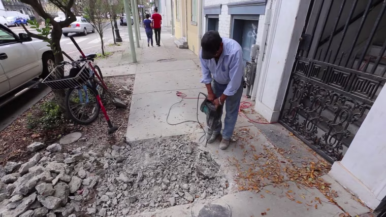 Searching for a lead pipe, a construction worker hammers into the sidewalk on New Orleans' Esplanade Avenue, lined with some of New Orleans' oldest homes. Older cities and properties built before 1950 are more likely to have lead service lines, which connect water mains to homes.