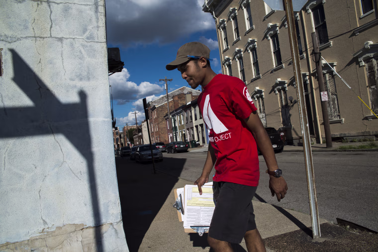 Image: Dallas Stokes, a volunteer for the AMOS Project, a nonprofit social justice organization in Cincinnati, registers people to vote