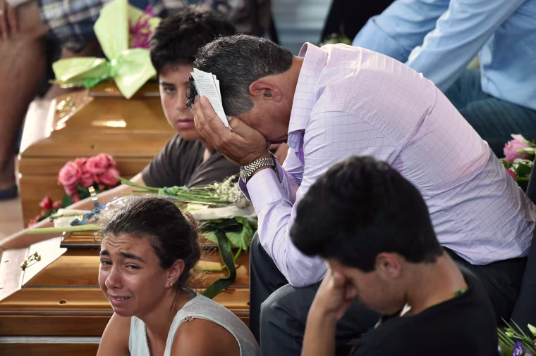 Image: Relatives mourn next to a coffin during a funeral service for victims of the earthquake