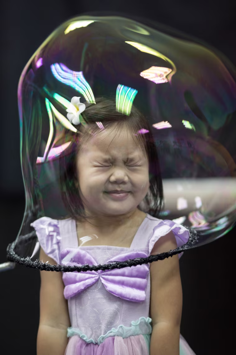 Image: A girl reacts as she stands in a soap bubble