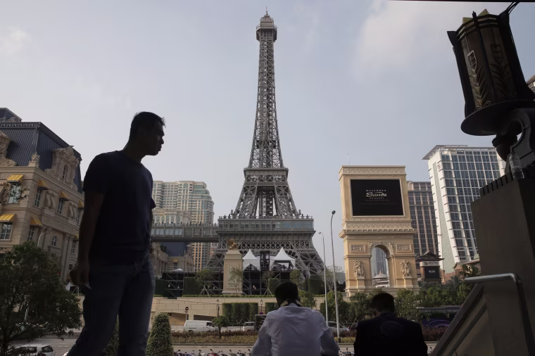 Image: People rest in front of a replica of the Eiffel Tower of Parisian Macao
