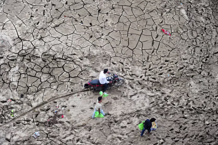 Image: People cross a marshland area on the bank of river Yaumna