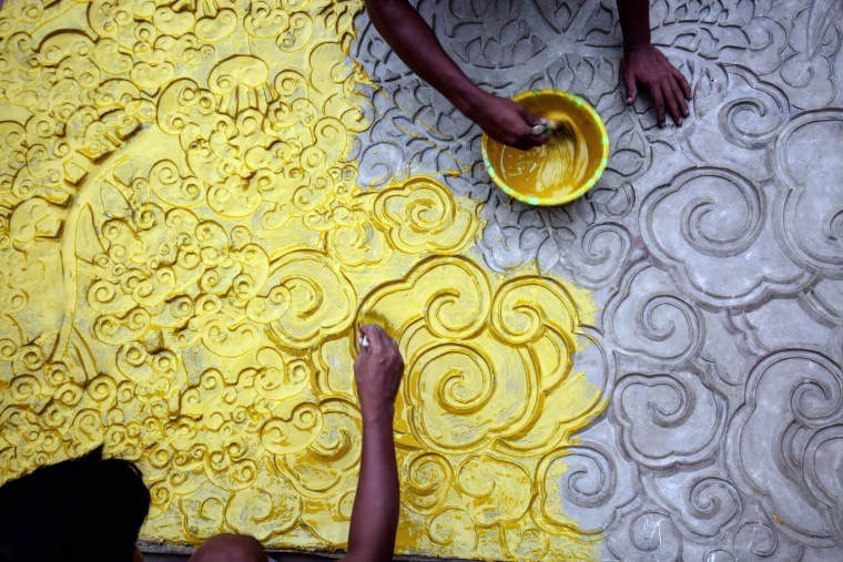 Image: Indian artists work on an art installation at a makeshift pandal