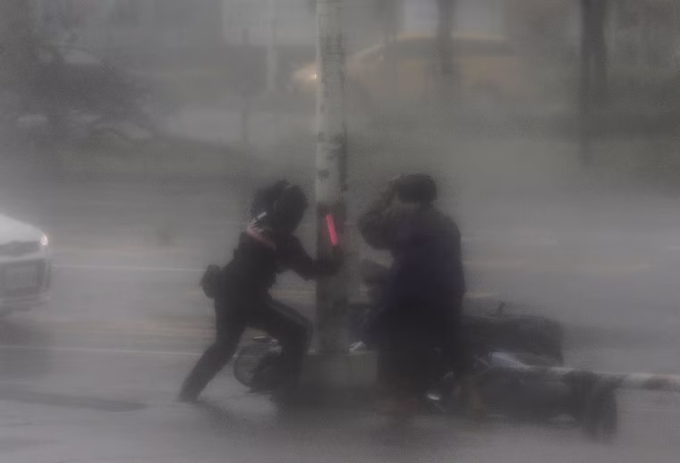 Image: A rescuer tries to assist a motorist victim as high winds and rain of Super Typhoon Meranti lash Kaohsiung