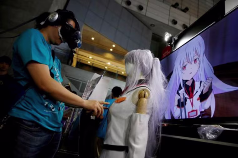 Image: A man touches a mannequin as he tries out a M2 Co.Ltd's "E-mote" system