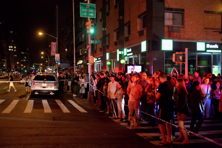 Image: Onlookers stand behind a police cordon near the site of an explosion in Manhattan, New York