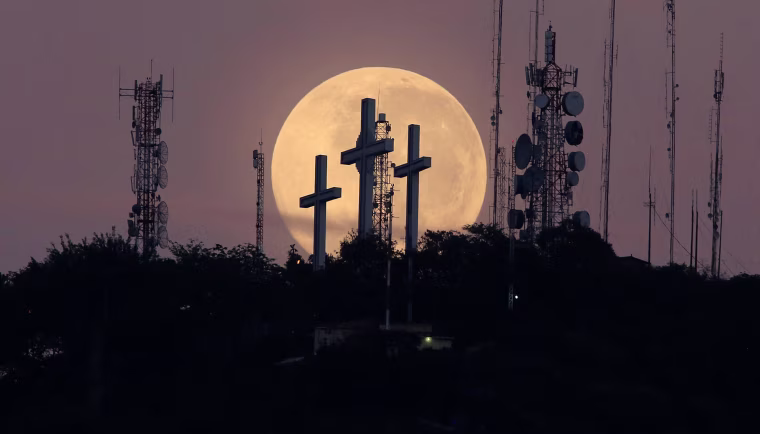 Image: The full moon is seen behind the hill of the three crosses in Cali