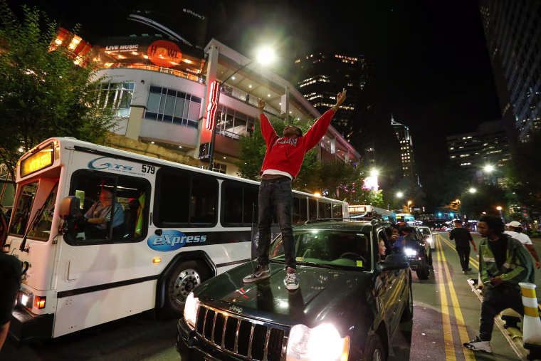 Image: A man stands on a car in uptown Charlotte, NC to protest the police shooting of Keith Scott, in Charlotte, North Carolina