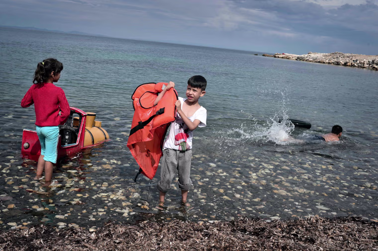 Image: Children play on the beach at an unofficial refugee site run by activists on the island of Lesbos