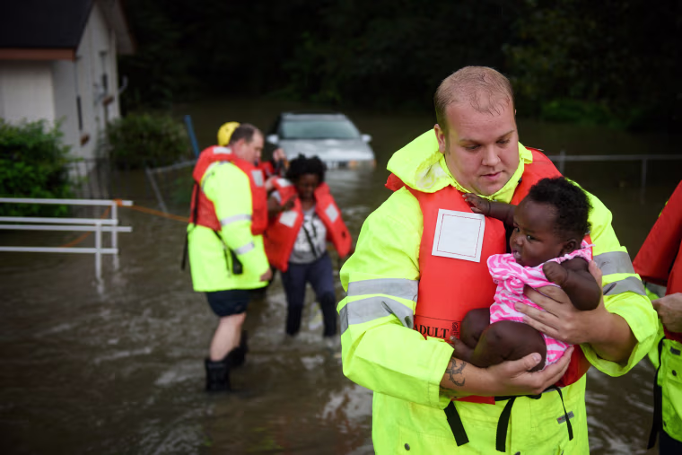 Image: A firefighter helps a family evacuate their flooded home in Fayetteville, N.C.