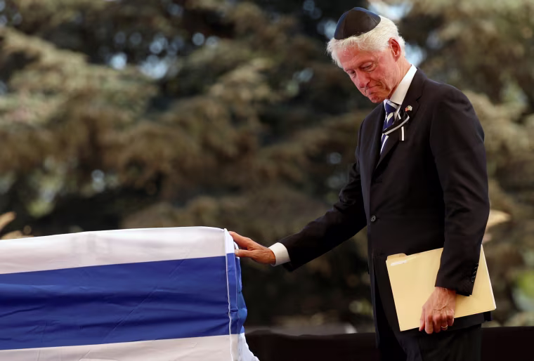 Image: Former US President Bill Clinton stands in front of the flag-draped coffin of the former Israeli President Shimon Peres
