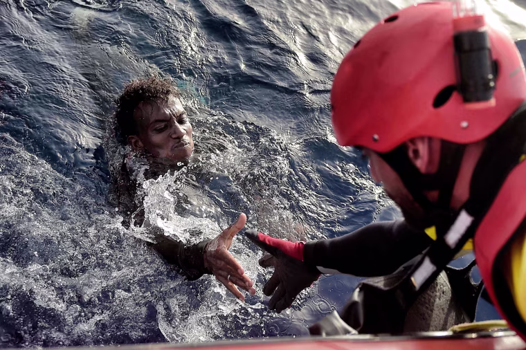 Image: A migrant is rescued from the mediteranean sea by a member of Proactiva Open Arms NGO