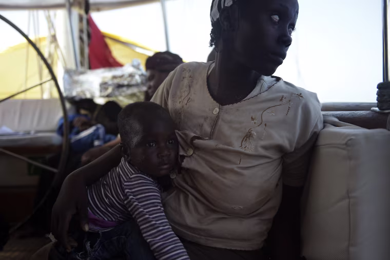 Image: A mother holds her child after migrants were rescued by members of Proactiva Open Arms NGO