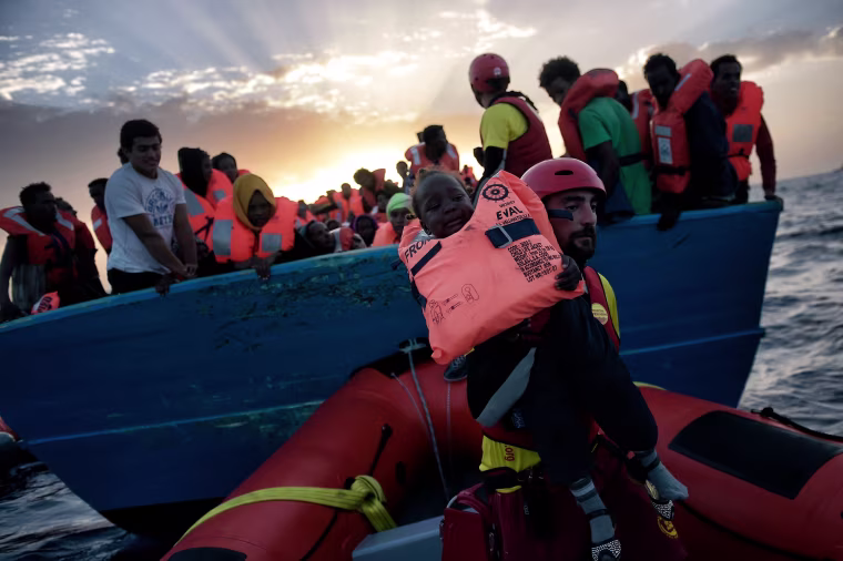 Image: A child from African origin is rescued from a distressed vessel by a member of Proactiva Open Arms NGO